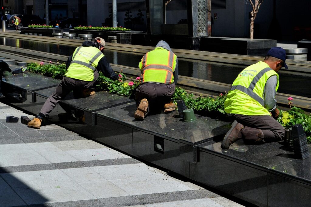 Drei  Gartenbau- Arbeiter bei der Pflege der Grünanlagen